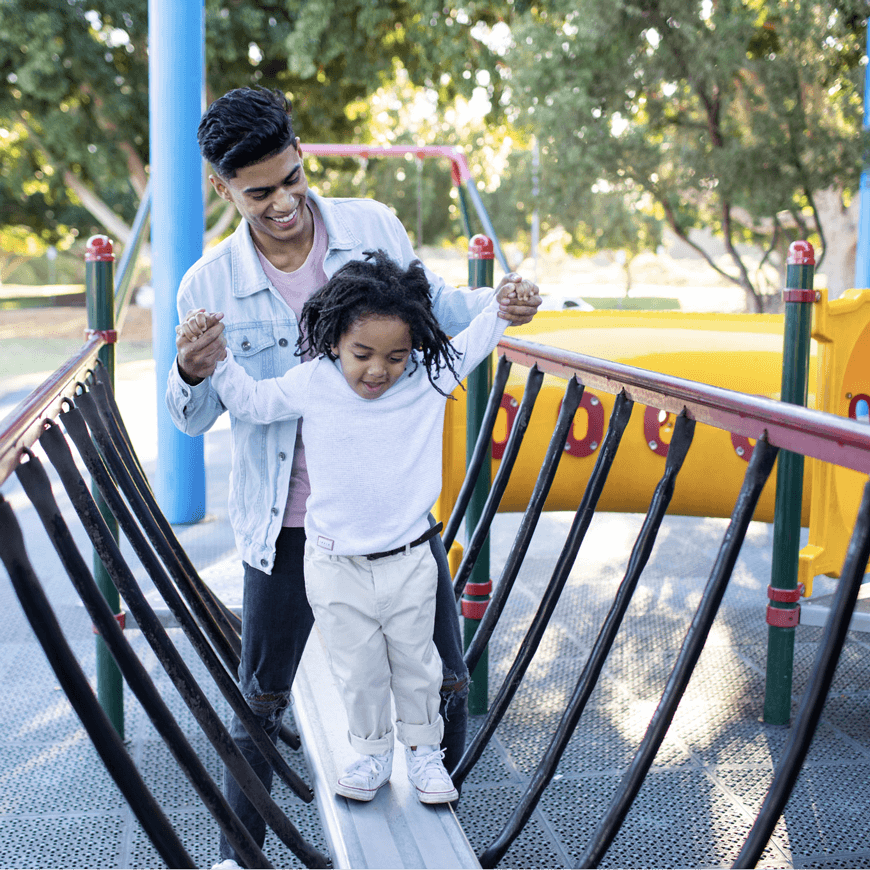 Young man playing with a small child at a playground.